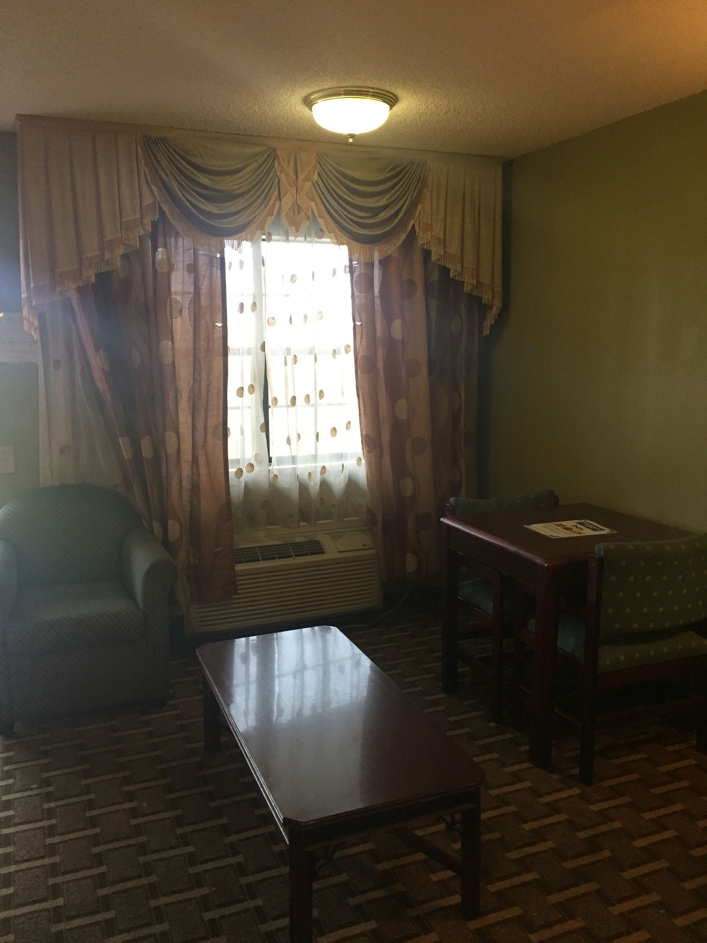 Una sala de estar con sofá, mesa, radiador y ventana con cortinas.