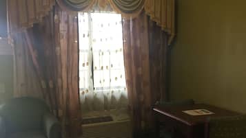 Una sala de estar con sofá, mesa, radiador y ventana con cortinas.