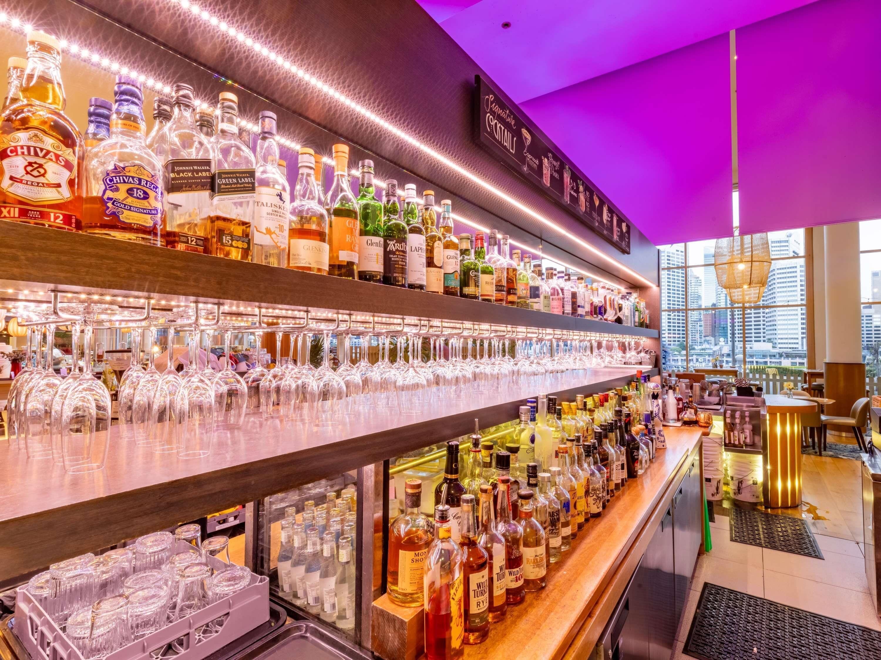 A bar area with shelves of liquor bottles and a variety of glasses.