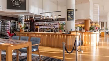 A modern bar area with a wooden counter, bar stools, and a wine rack in the background.