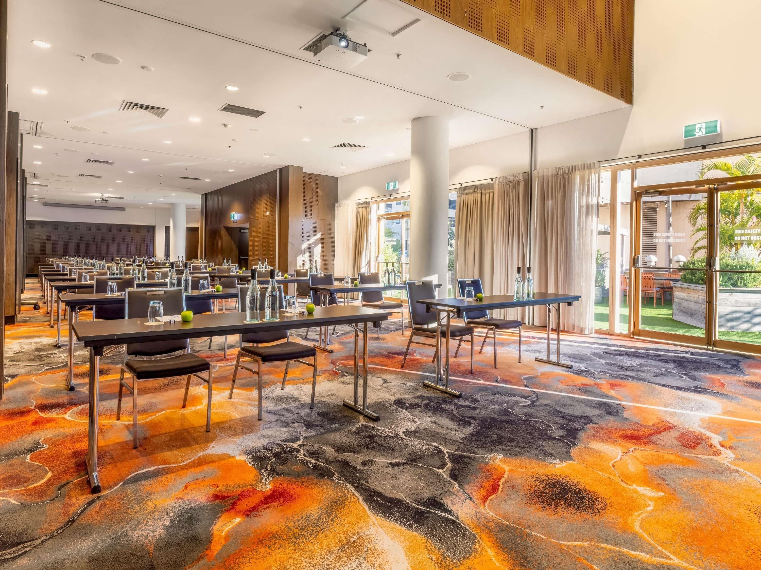 A hotel conference room with tables, chairs, and a carpeted floor.