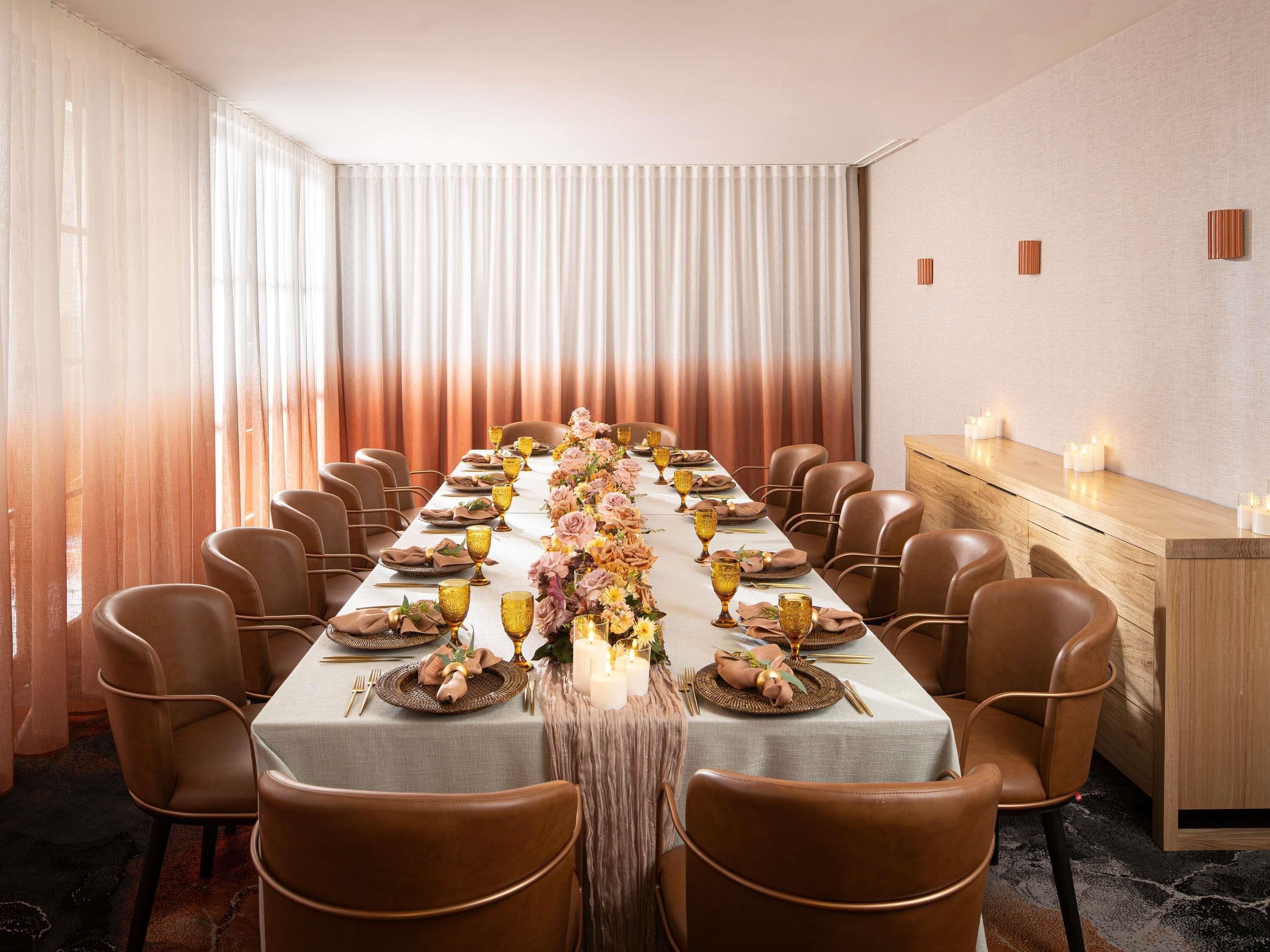 A long dining table set with chairs, candles, and floral centerpieces.
