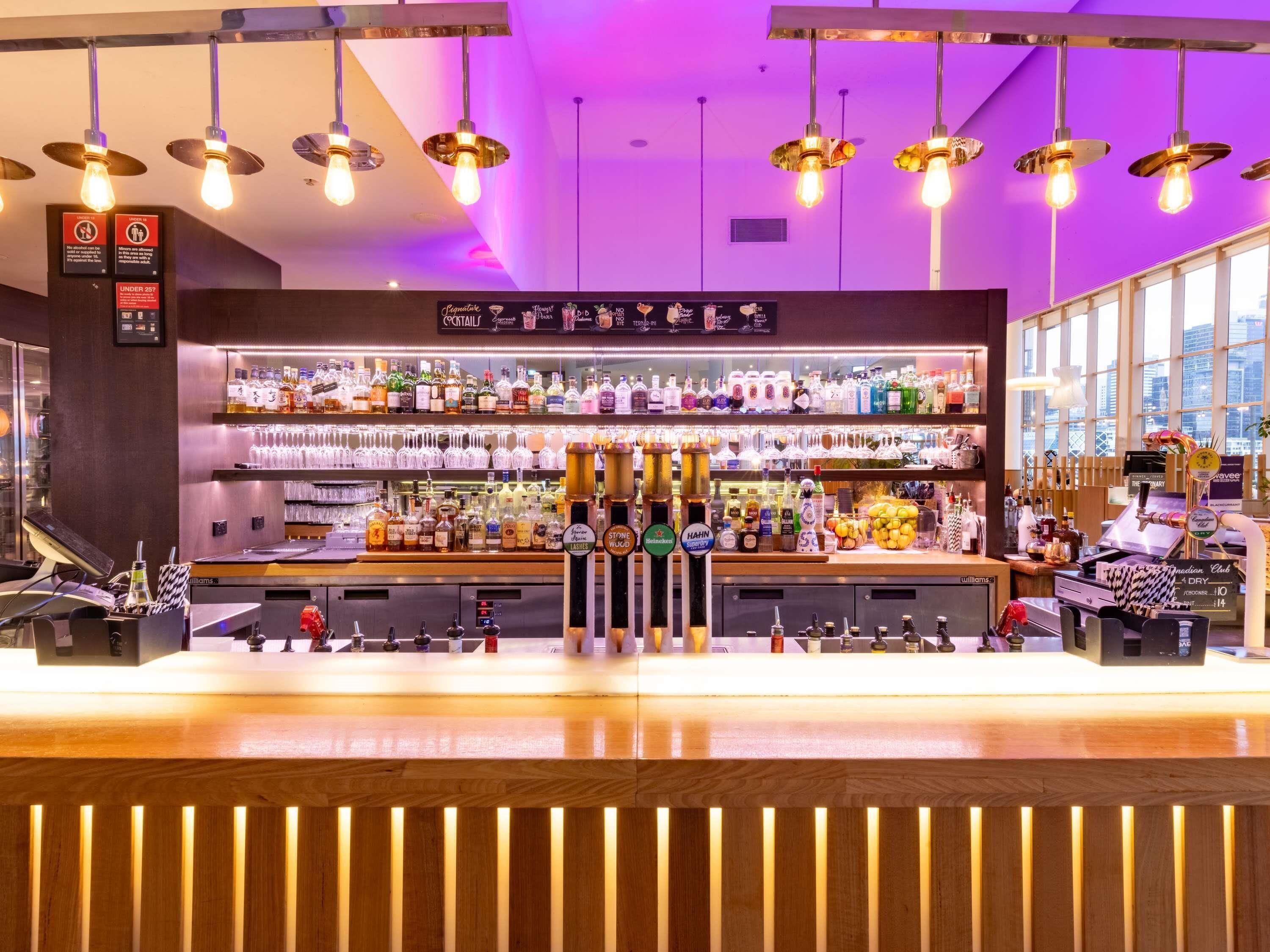 A bar area with a variety of liquor bottles, a selection of glasses, and a bar counter.