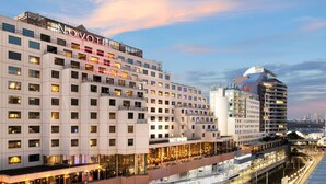 Un hotel moderno con varios pisos, un paseo techado y una estructura de estacionamiento.