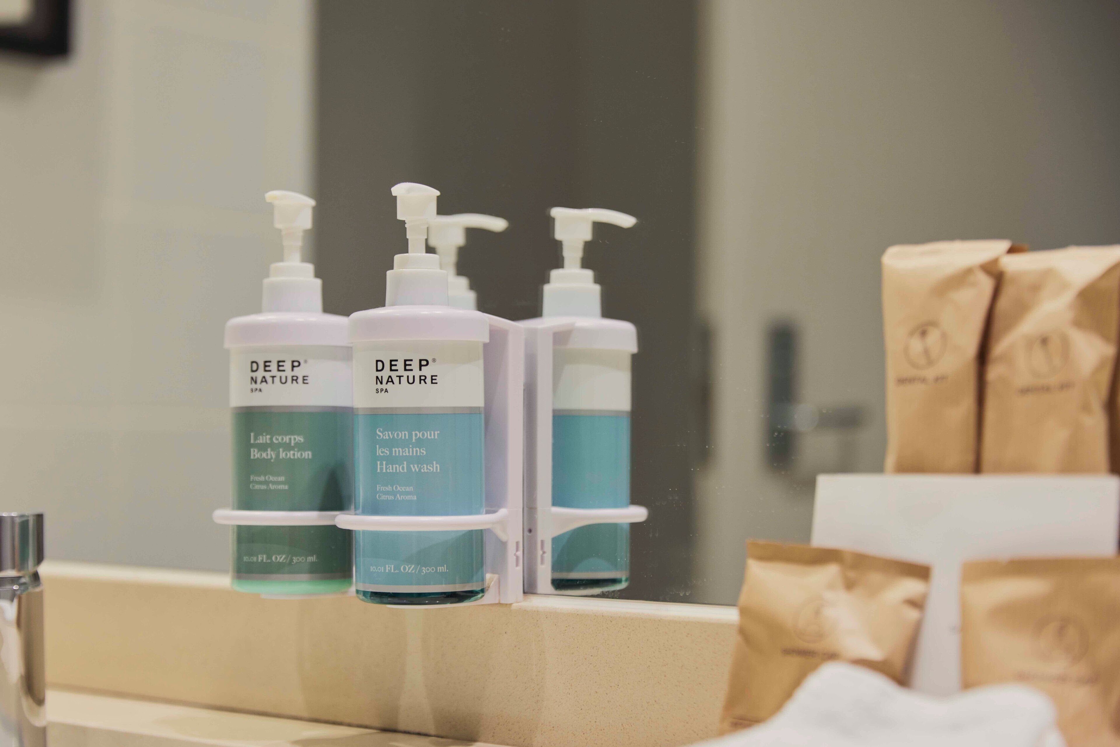 Three bottles of Deep Nature spa body lotion and hand wash on a bathroom counter.
