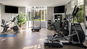 A modern gym with various exercise equipment, large windows, and a flat-screen TV. - City Express by Marriott Santa Ana/Orange County Airport (Santa Ana)
