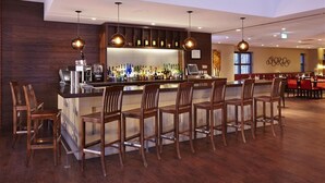 A bar area with wooden chairs and a bar counter stocked with bottles.