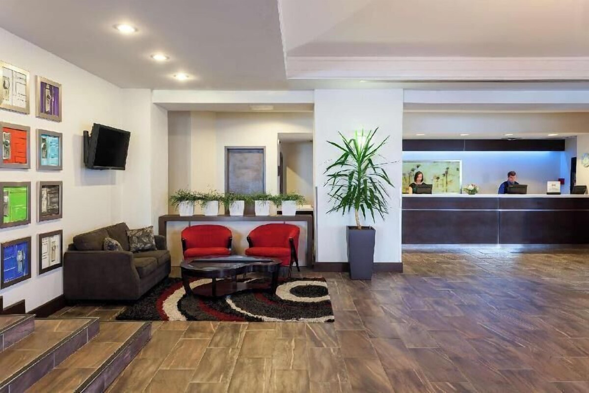 A modern lobby with a reception desk, red chairs, a sofa, and a coffee table.