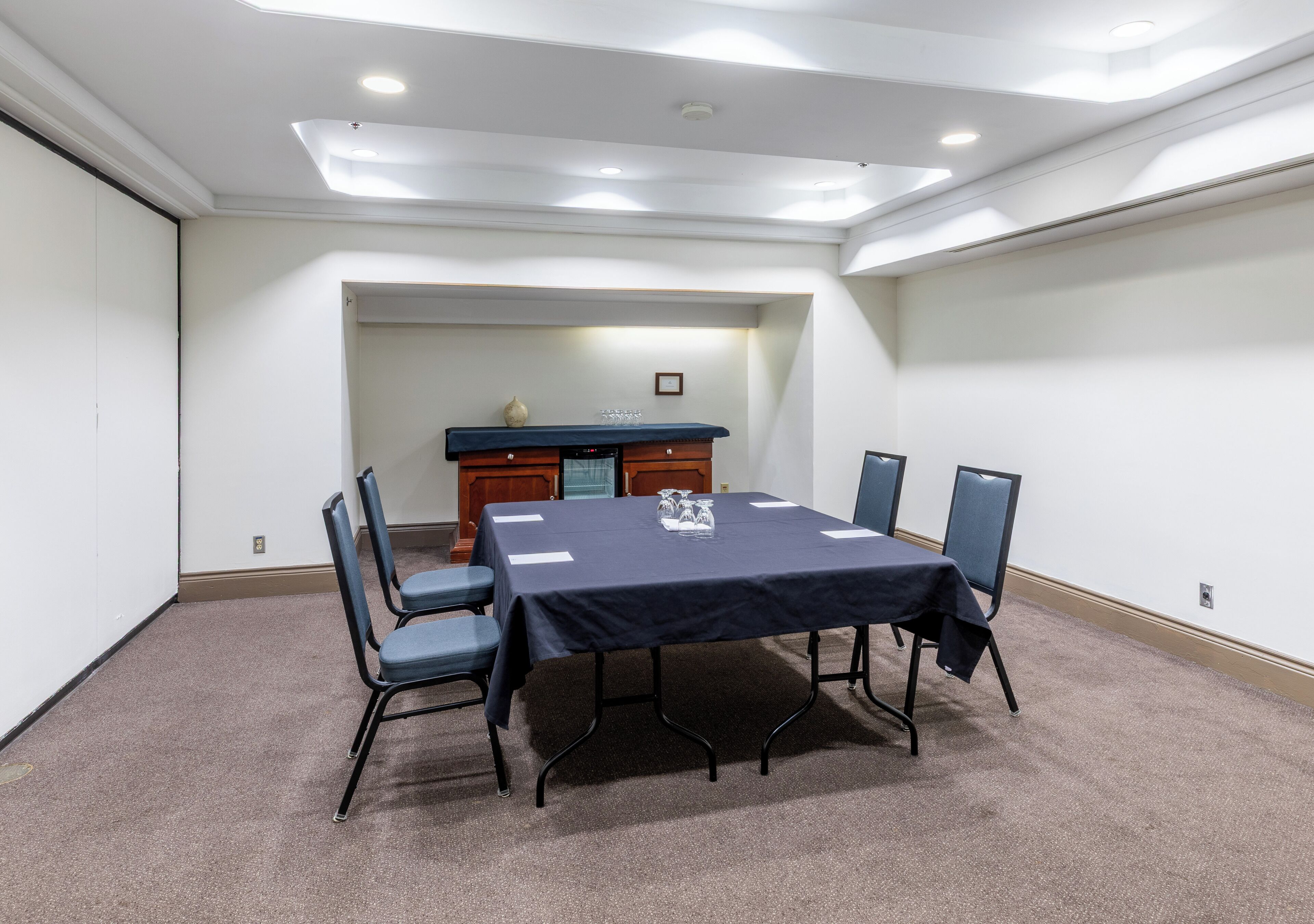 Une salle de conférence équipée d’une table, de chaises, d’un pupitre et d’un sol recouvert de moquette.