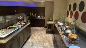 A buffet area with a variety of food items, a coffee station, and a fruit display.