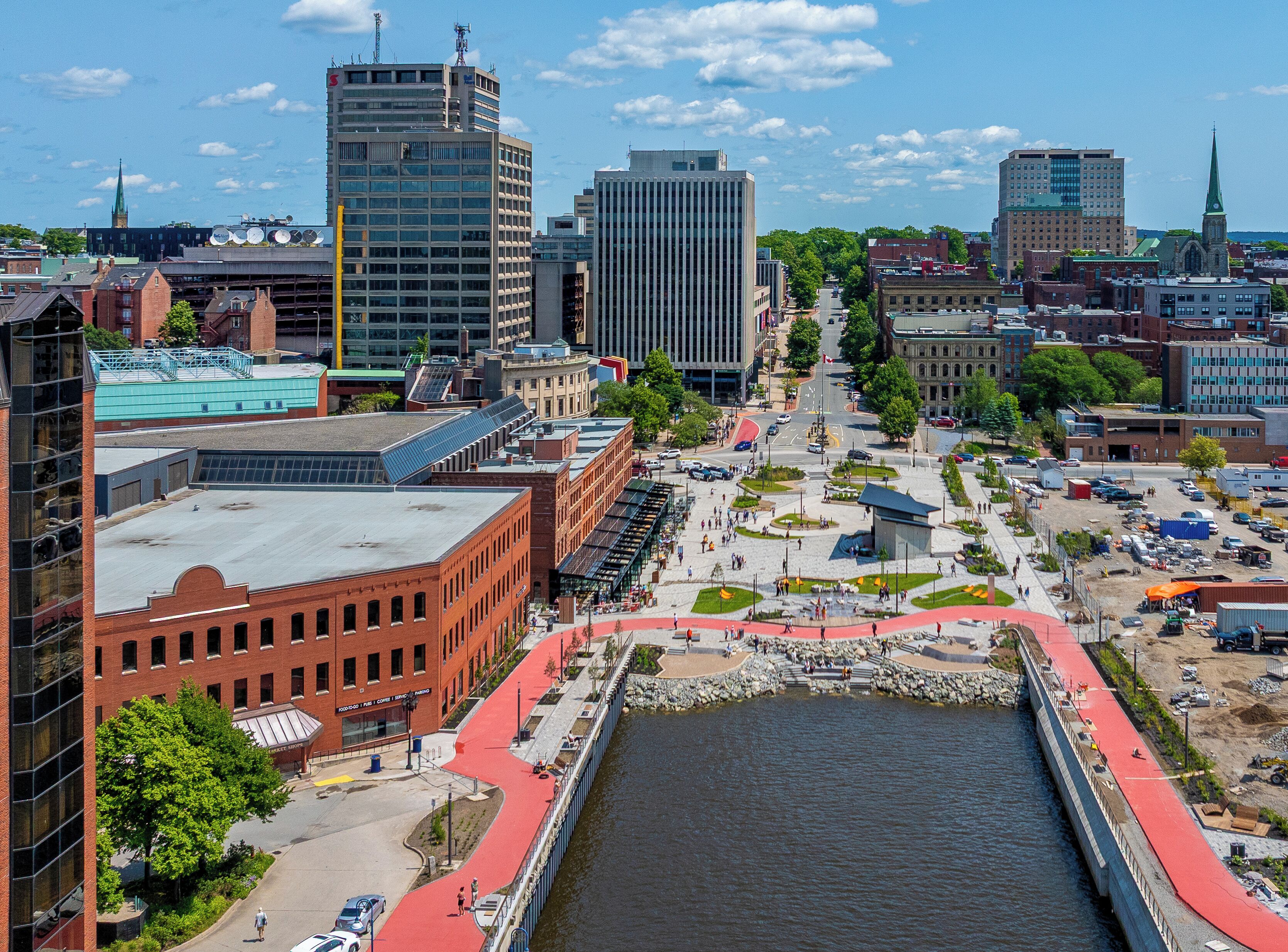 A cityscape with a prominent river, modern buildings, and a pedestrian bridge.