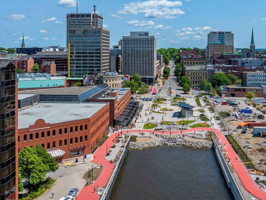 A cityscape with a prominent river, modern buildings, and a pedestrian bridge.