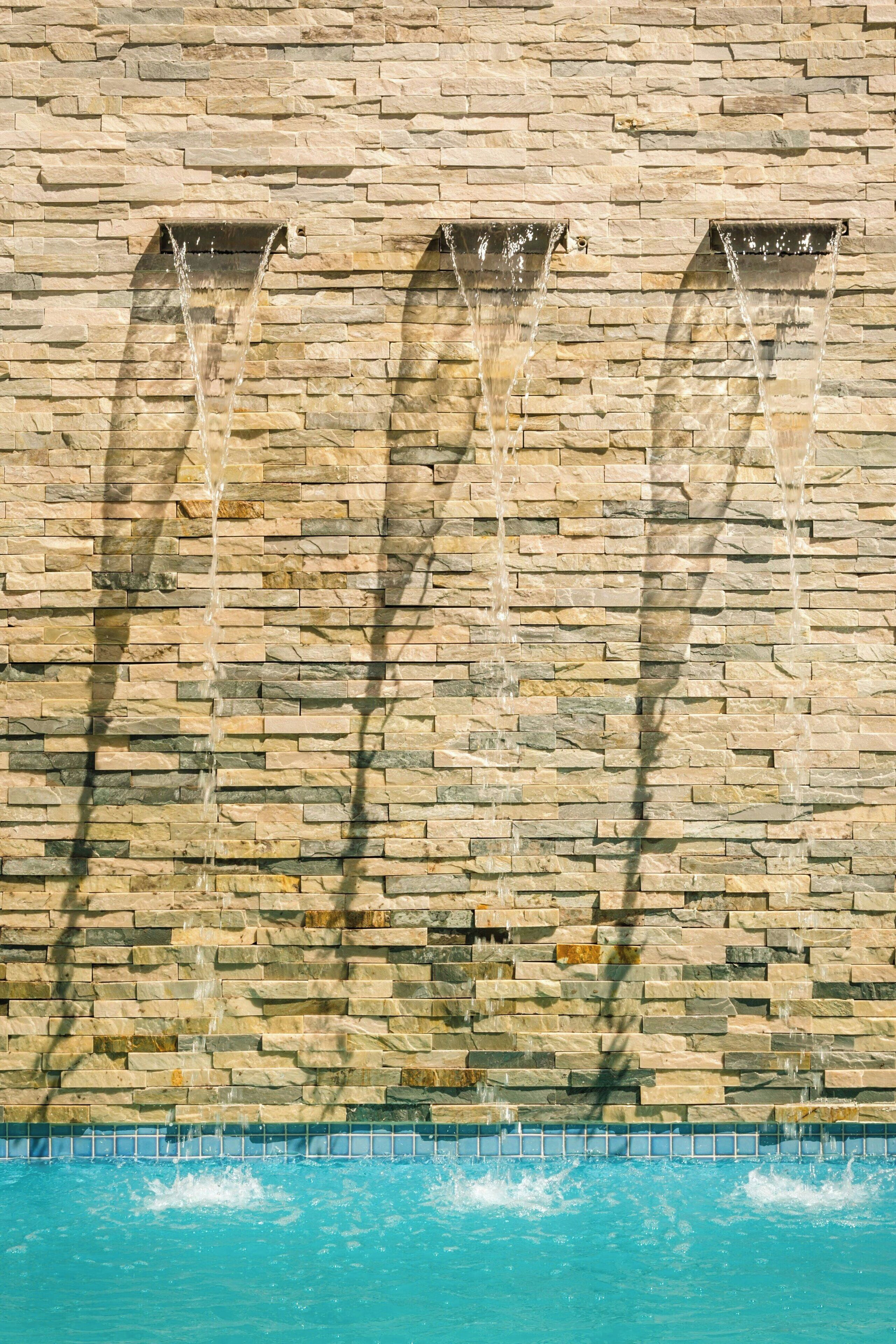 A stone wall with three water features.