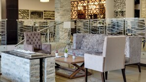 Un espace de détente moderne avec une cheminée en pierre, des sièges confortables et une balustrade en verre.