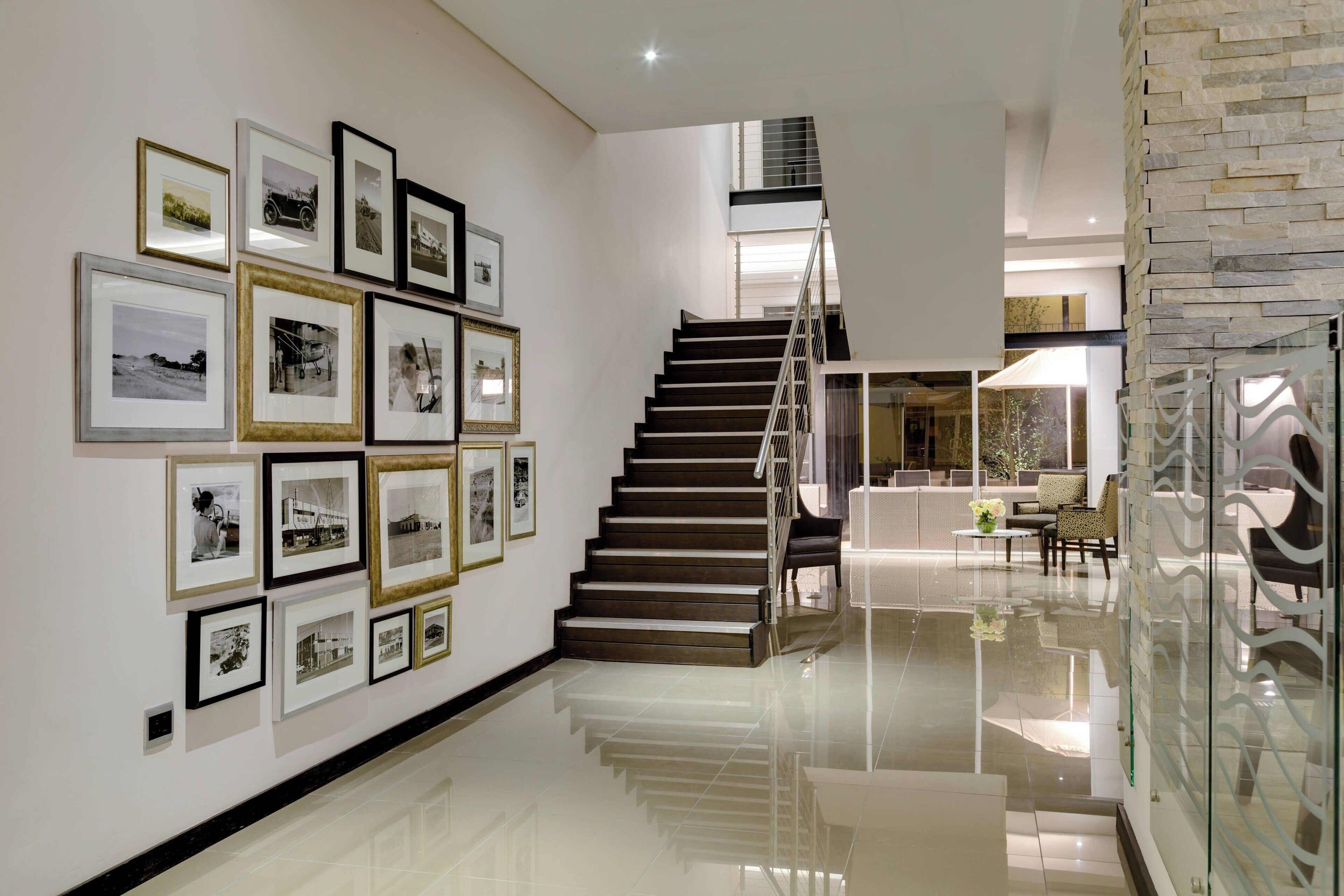 A modern interior with a staircase, framed pictures on the wall, and a glass partition.