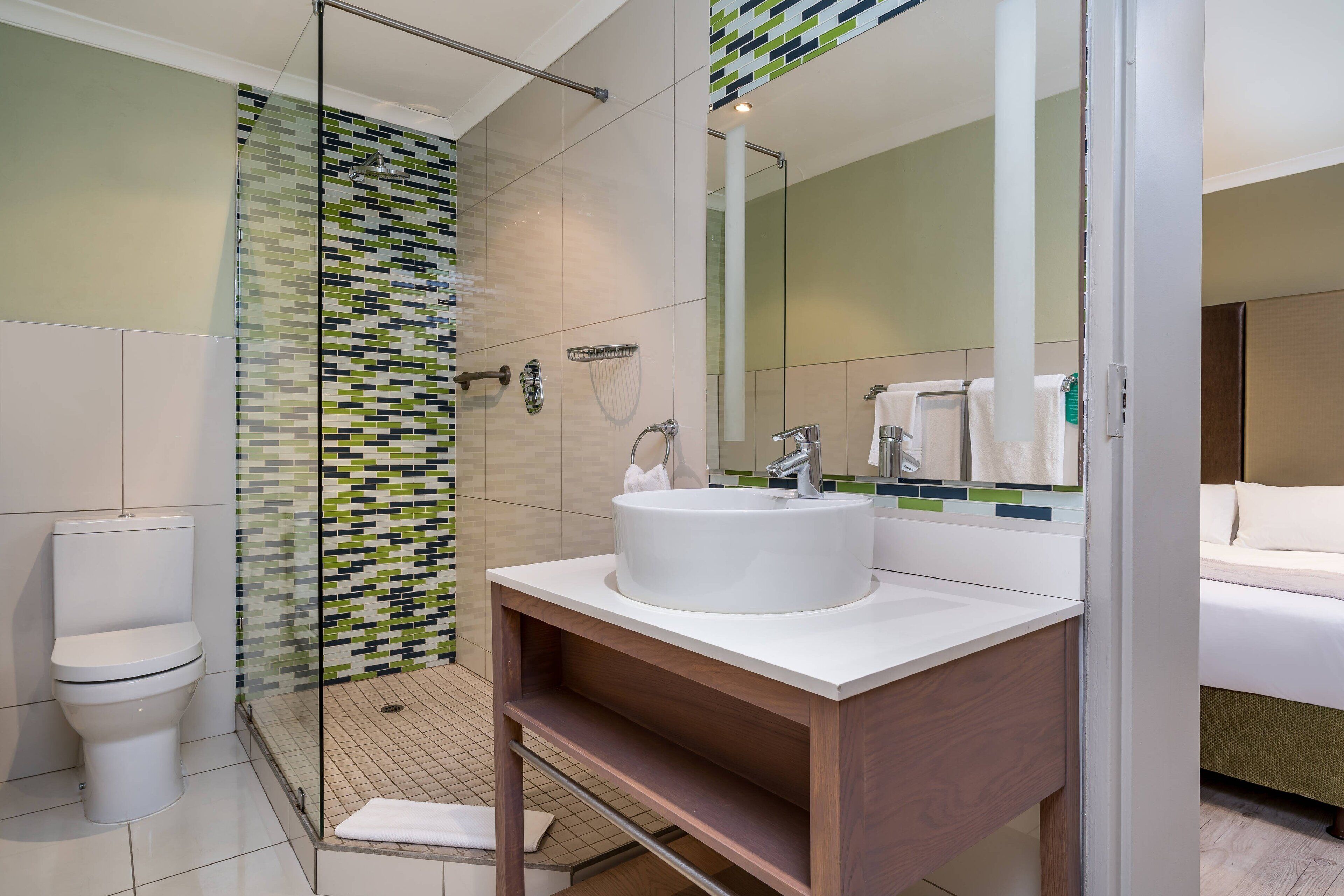 A modern bathroom with a glass shower enclosure, a white sink, and a large mirror.