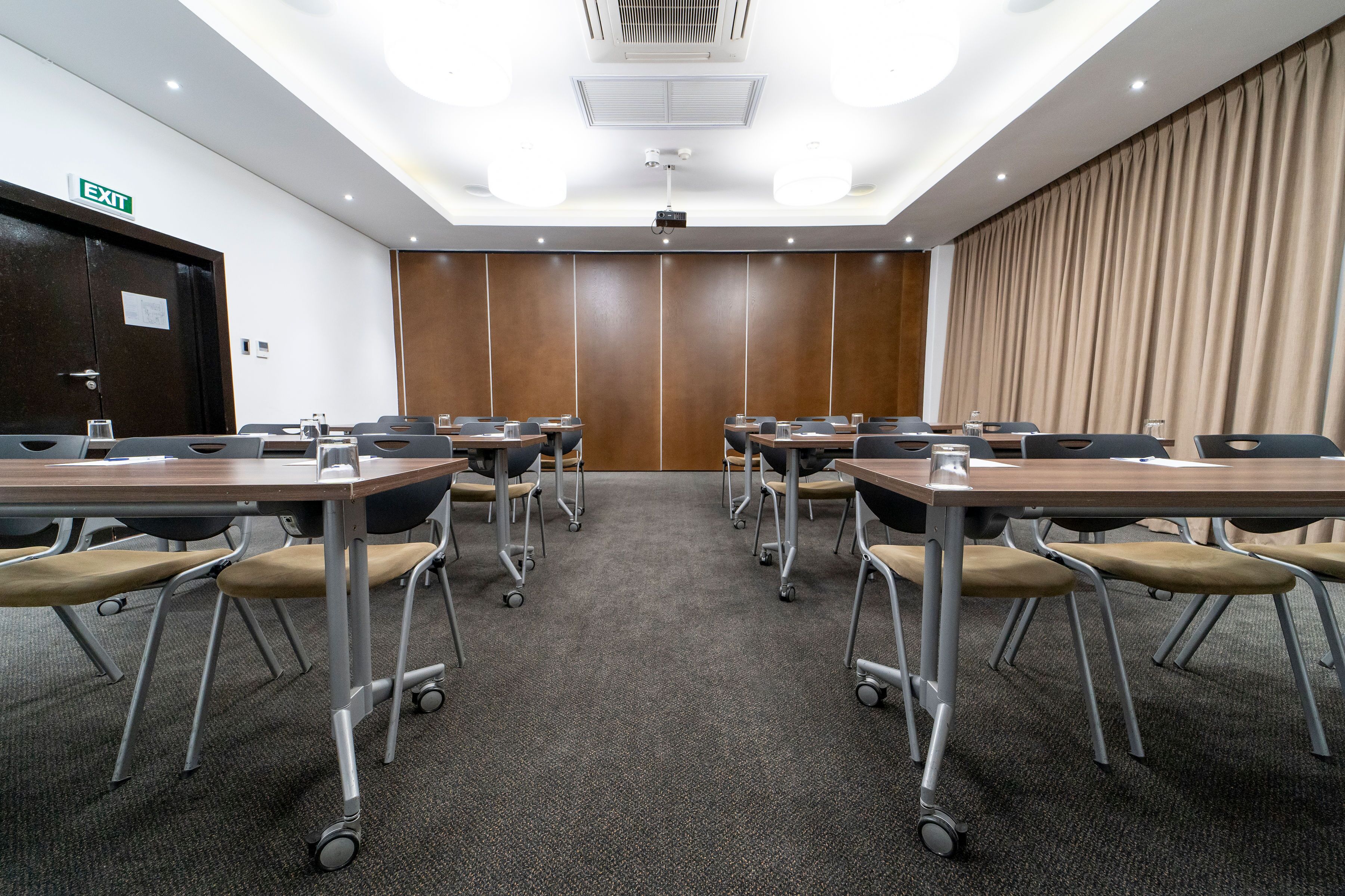 A conference room with a projector, a large curtain, and a door marked "EXIT".