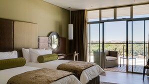 Une chambre d’hôtel avec deux lits, une grande fenêtre, un balcon et une vue sur la campagne.