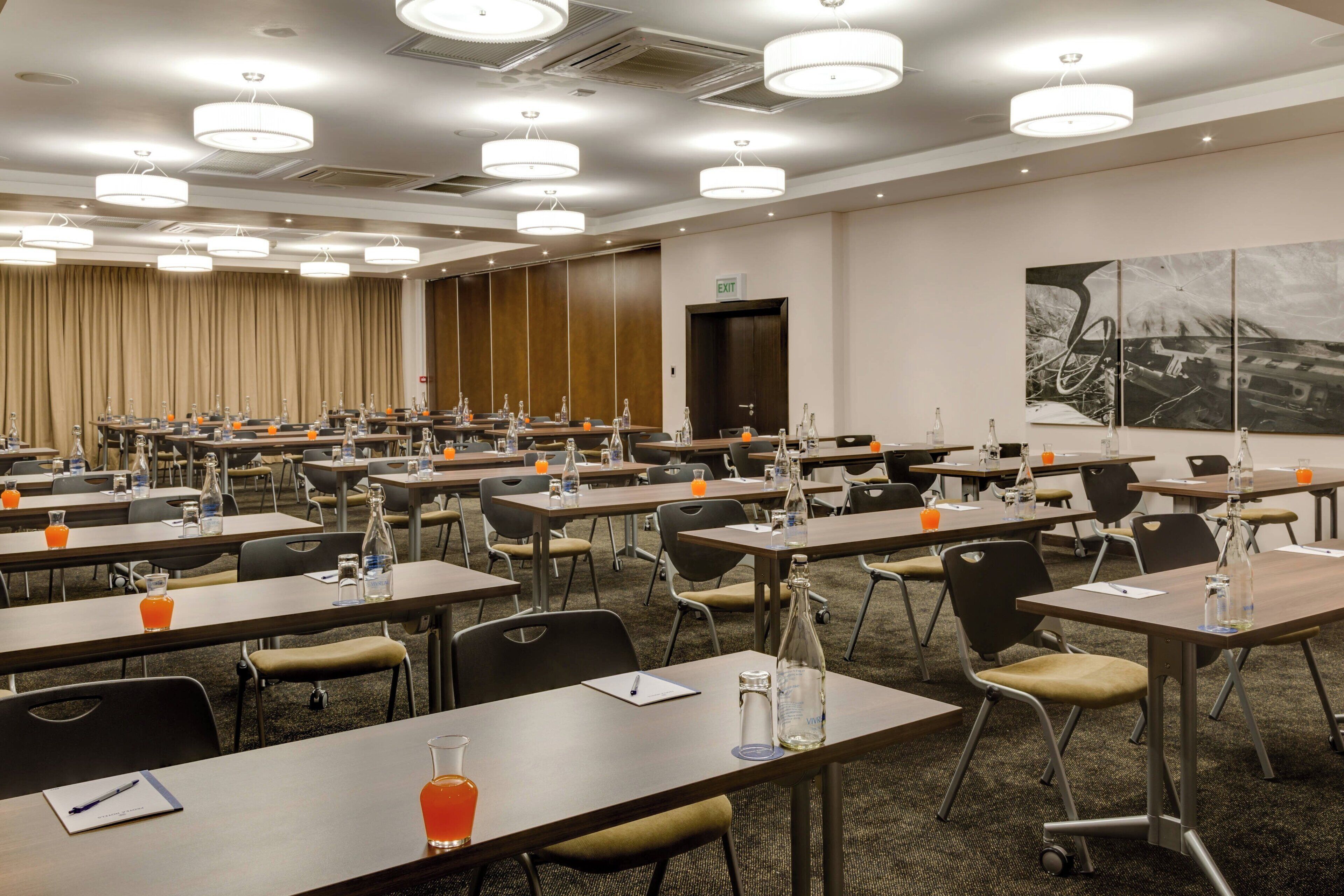 A conference room with multiple tables, chairs, and a large painting on the wall.