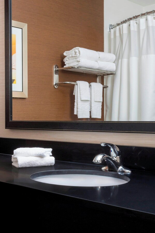 A bathroom with a black sink, a mirror, and a towel rack with folded towels.