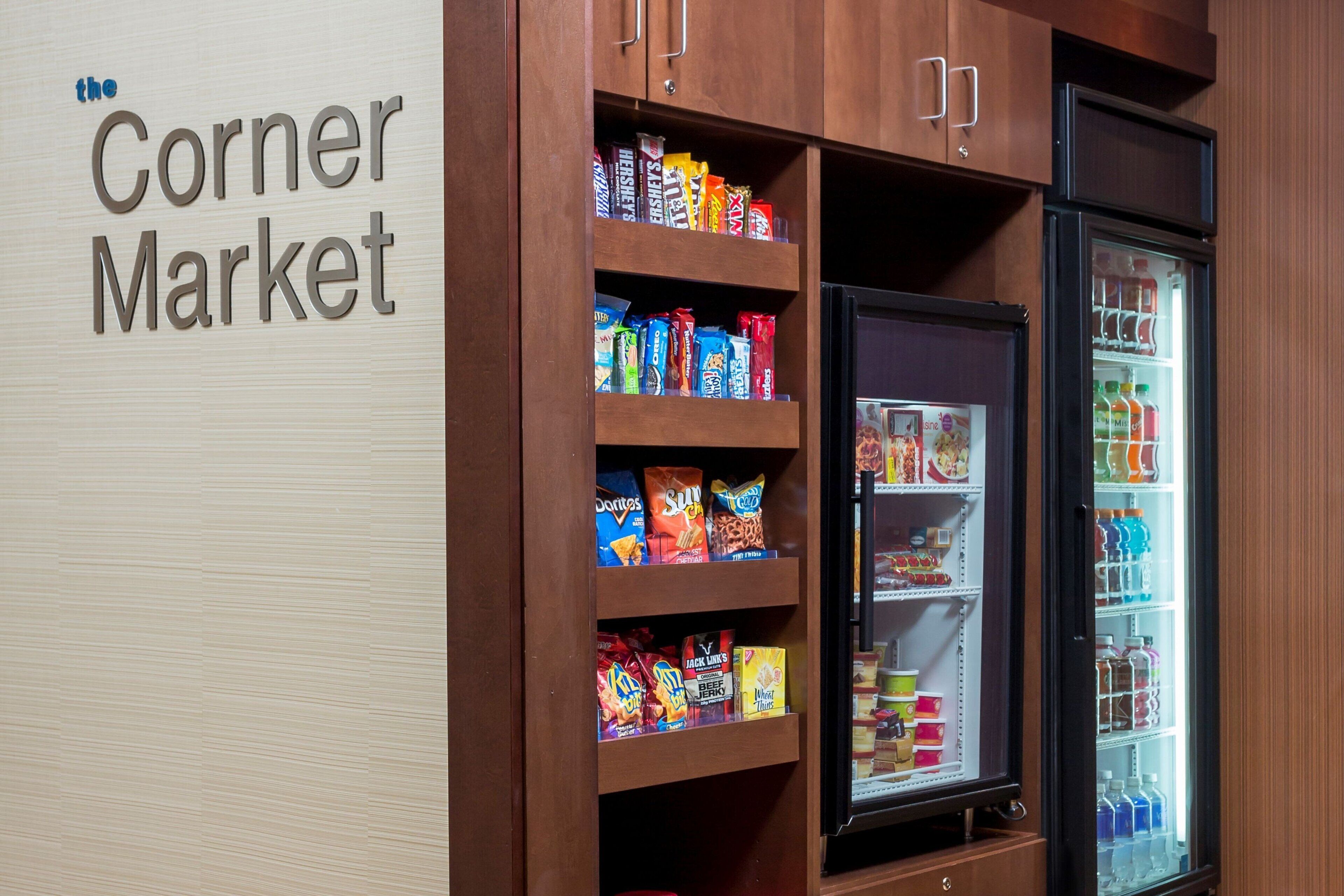 Un mercado de barrio con estantes llenos de refrigerios y una vitrina refrigerada.