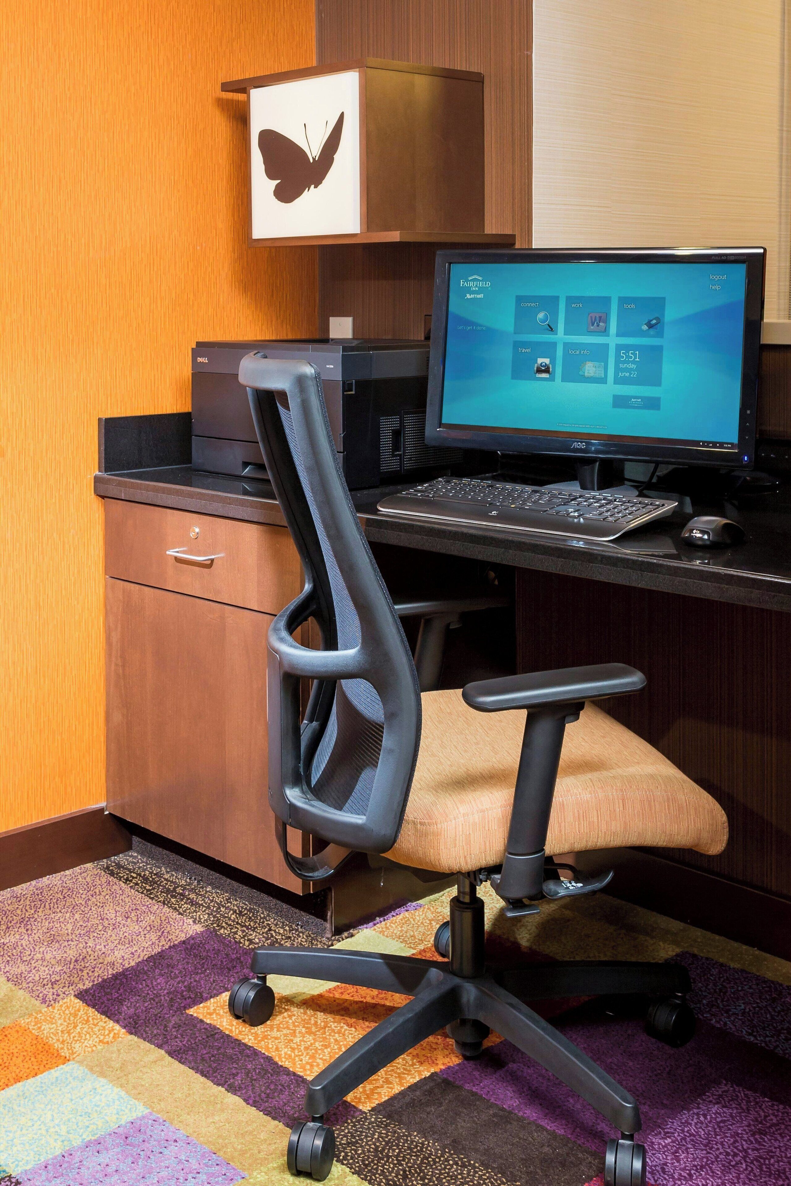 Una habitación de hotel con escritorio, computadora y una silla.