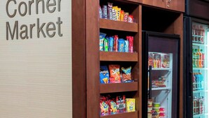 Une petite épicerie de quartier avec des étagères et des armoires en bois, remplies de collations, et un présentoir réfrigéré.