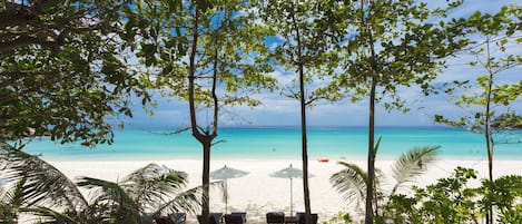 Een privéstrand, wit zand, ligstoelen aan het strand, parasols