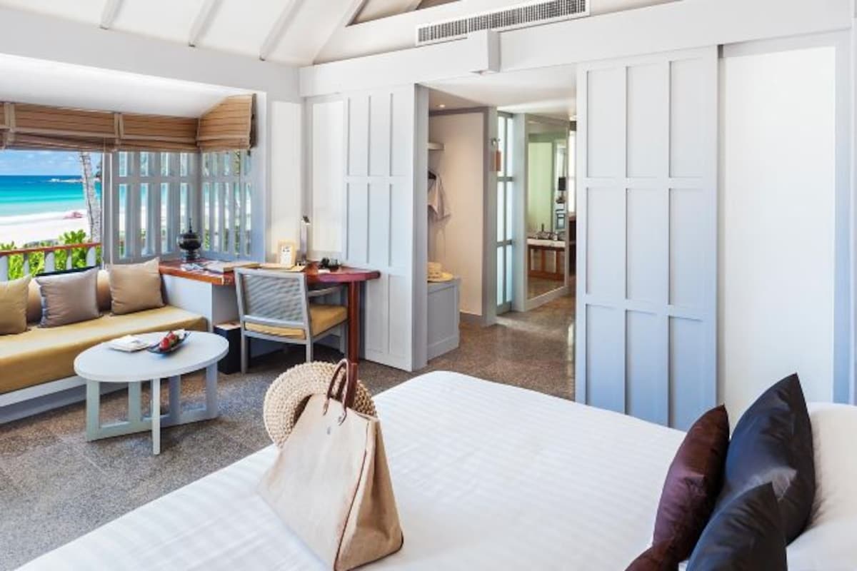 A hotel room with a bed, a sofa, a desk, and a view of the beach.