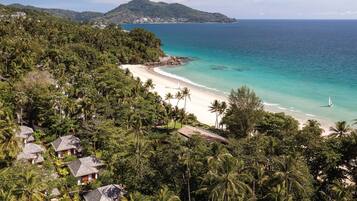 A tropical beach with a clear view of the ocean, a sandy beach, and lush greenery.