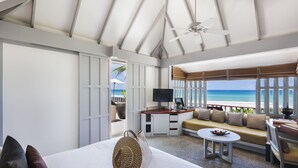 A hotel room with a bed, a sofa, a TV, and a view of the ocean.