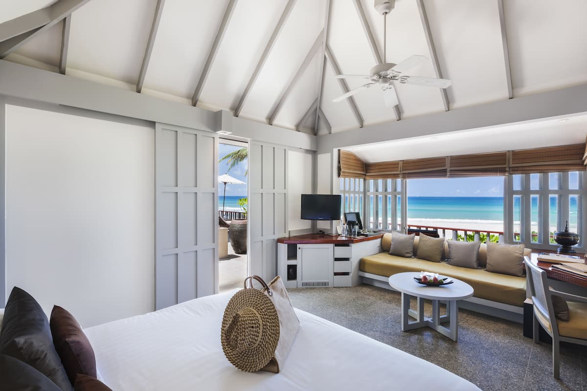A hotel room with a bed, a sofa, a TV, and a view of the ocean.
