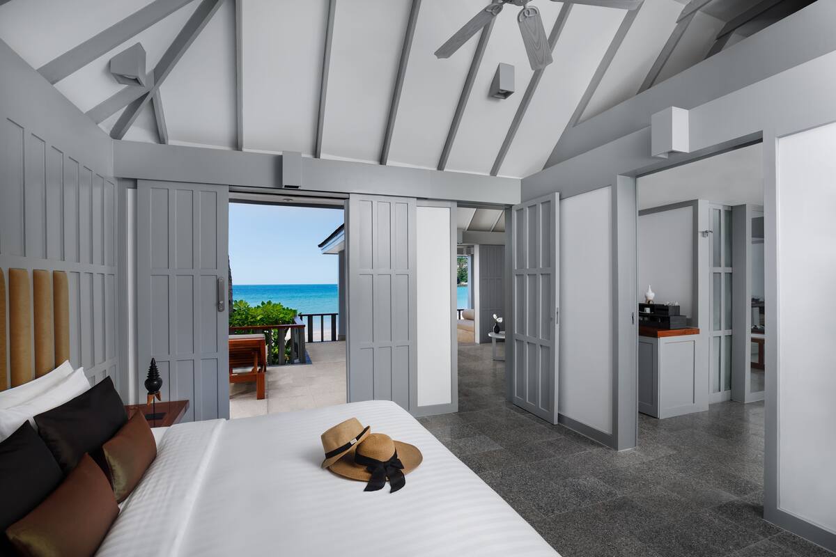 A modern hotel room with a large bed, a view of the ocean, and a balcony.