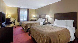 Habitación de hotel con dos camas, un escritorio con computadora, televisión y lámparas.