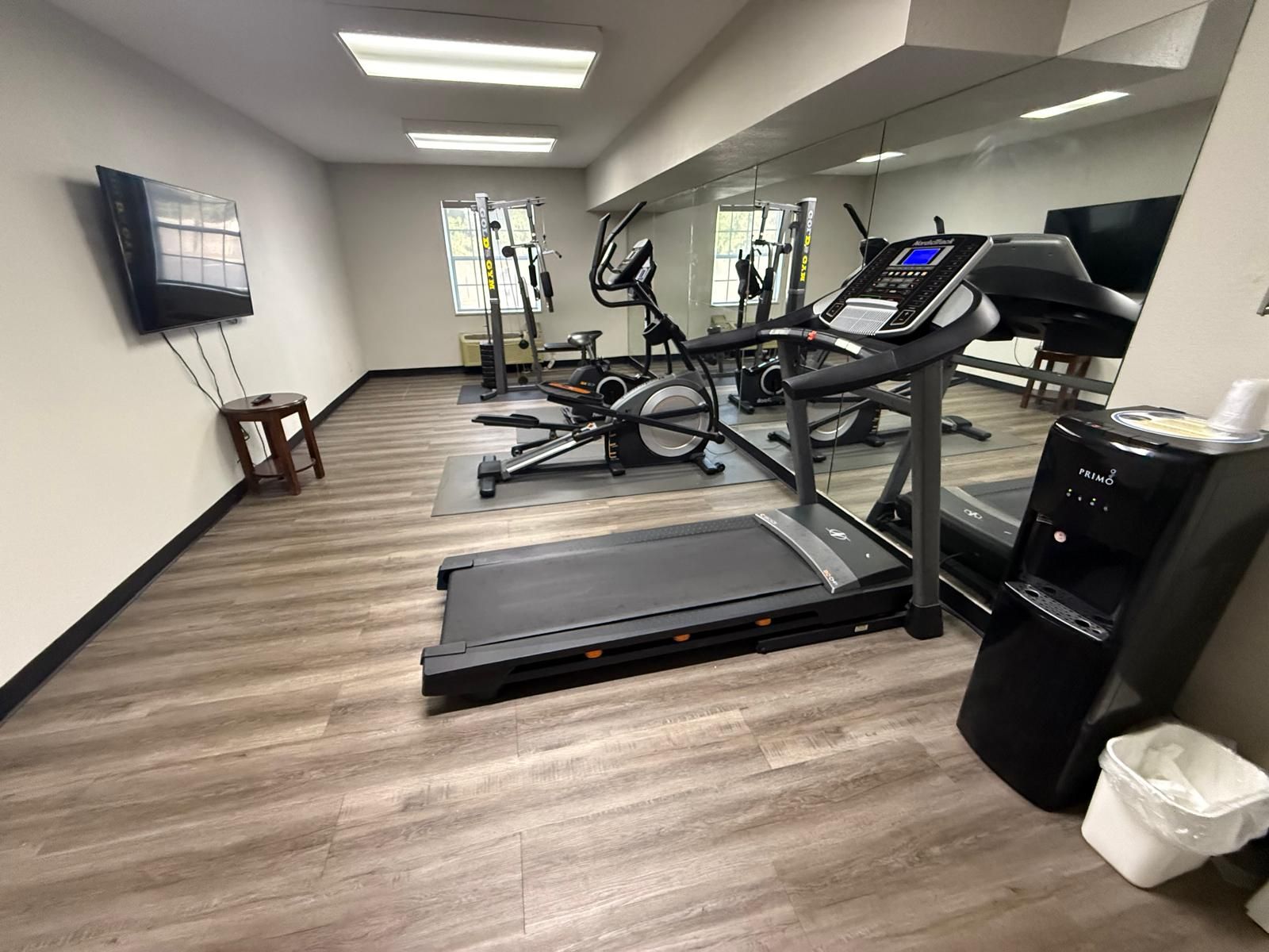 A gym with cardio equipment, a mirror, and a water dispenser.