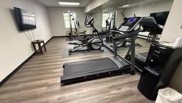A gym with cardio equipment, a mirror, and a water dispenser.