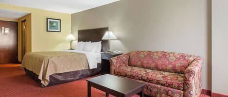 A hotel room with a bed, a sofa, a table, and two lamps.