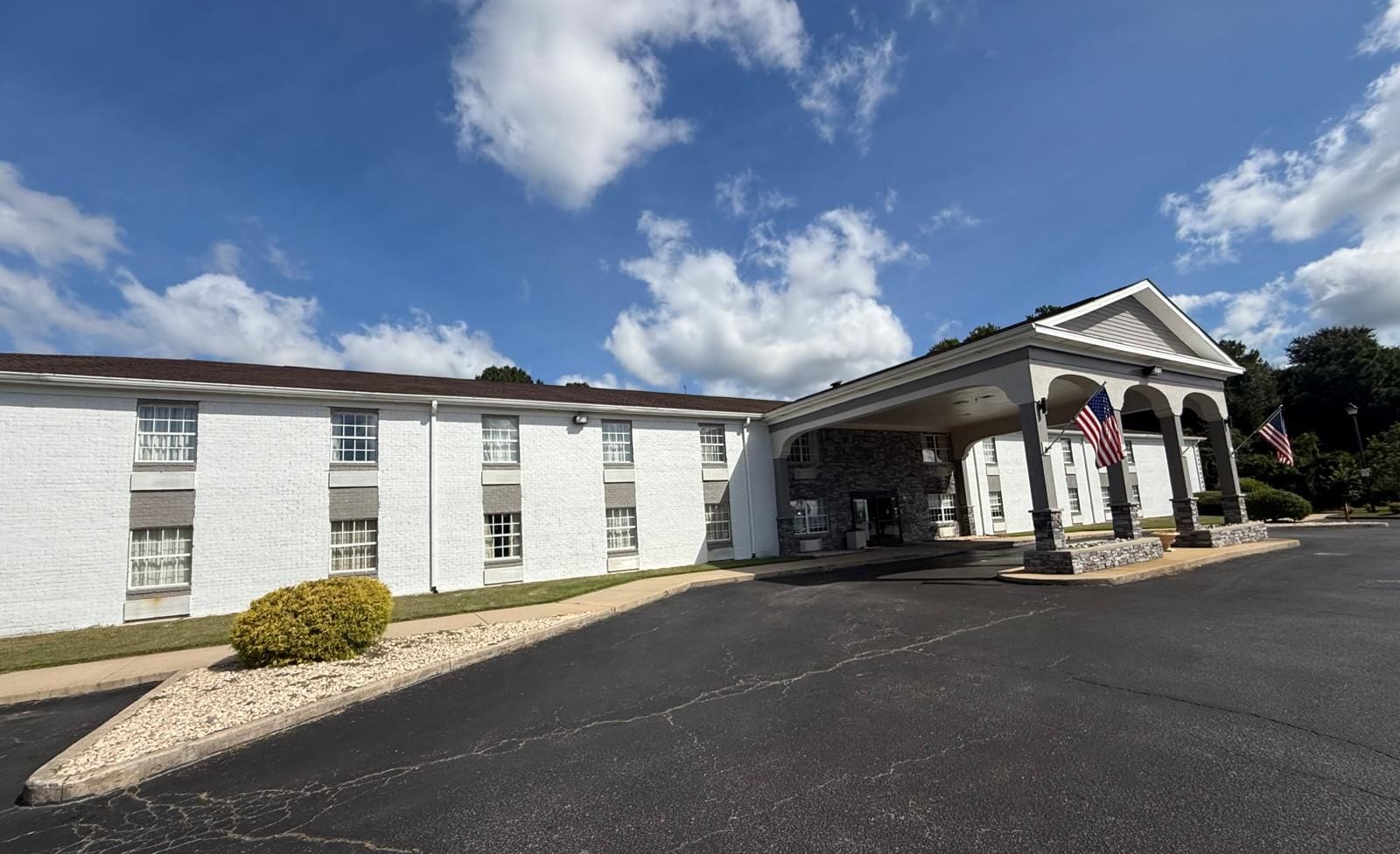 A building with a covered entrance, American flags, and a parking lot.