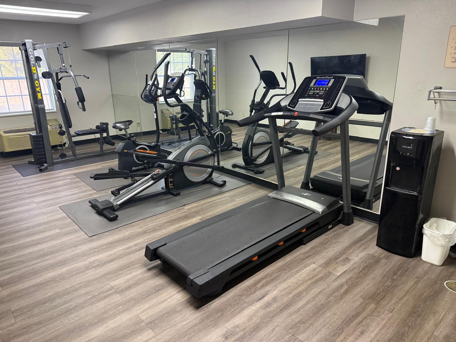 Un gimnasio con máquinas de cardio, equipo de pesas y un dispensador de agua.