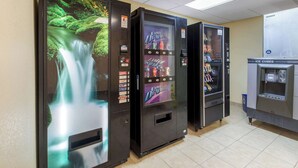 Tres máquinas expendedoras: una con una imagen de cascada a la izquierda, una máquina de bebidas frías en el centro y una máquina de hielo a la derecha.
