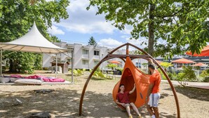 Un parque infantil con columpios y una zona de estar techada.