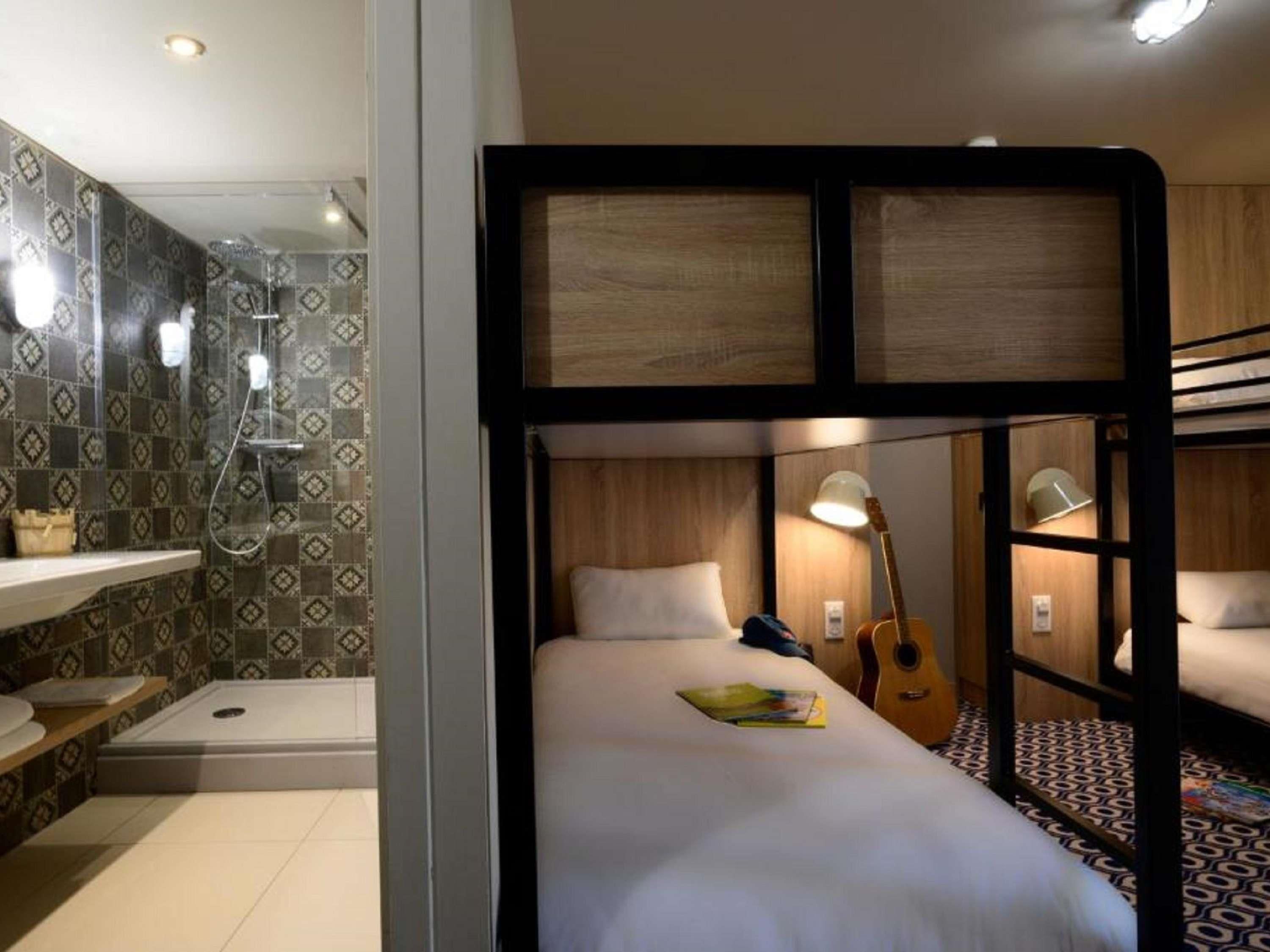 A bunk bed room with a shower, a guitar, and a lamp.