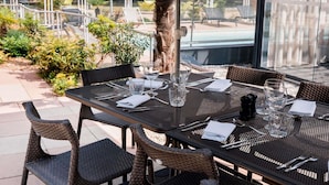 Un espacio de comedor al aire libre con mesas, sillas y sombrillas.