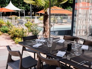 Un espace extérieur aménagé pour les repas, avec des tables, des chaises et des parasols.