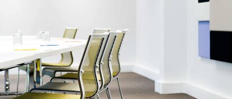 A conference room with a white table, metal chairs, and a carpeted floor.