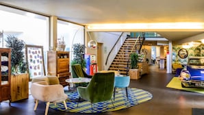 Un hall amplio con una escalera, mobiliario moderno y una exhibición de coches antiguos.