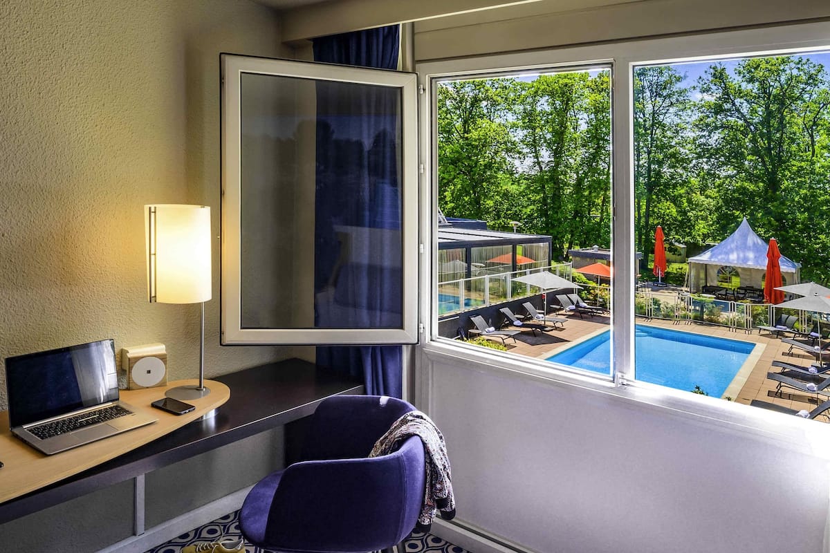 Habitación de hotel con vista a una piscina exterior y zona de estar.