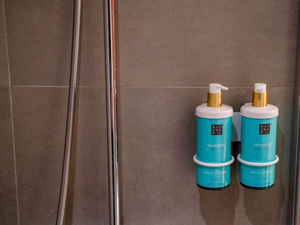 Two bottles of The Ritual of Karma shampoo and shower gel on a tiled wall.