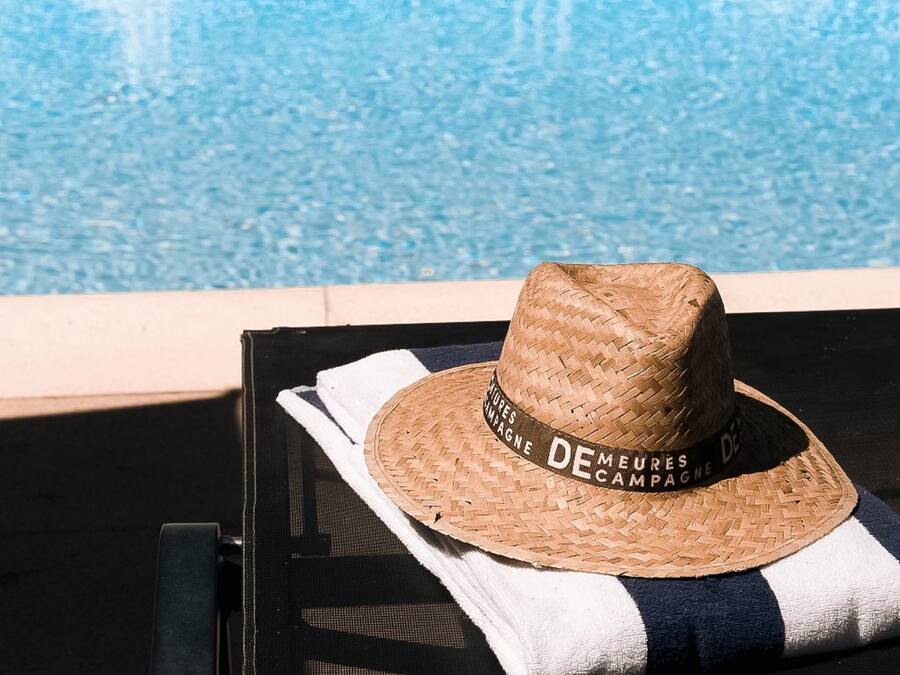 En halmhat med tekst placeret på et håndklæde ved siden af en pool.