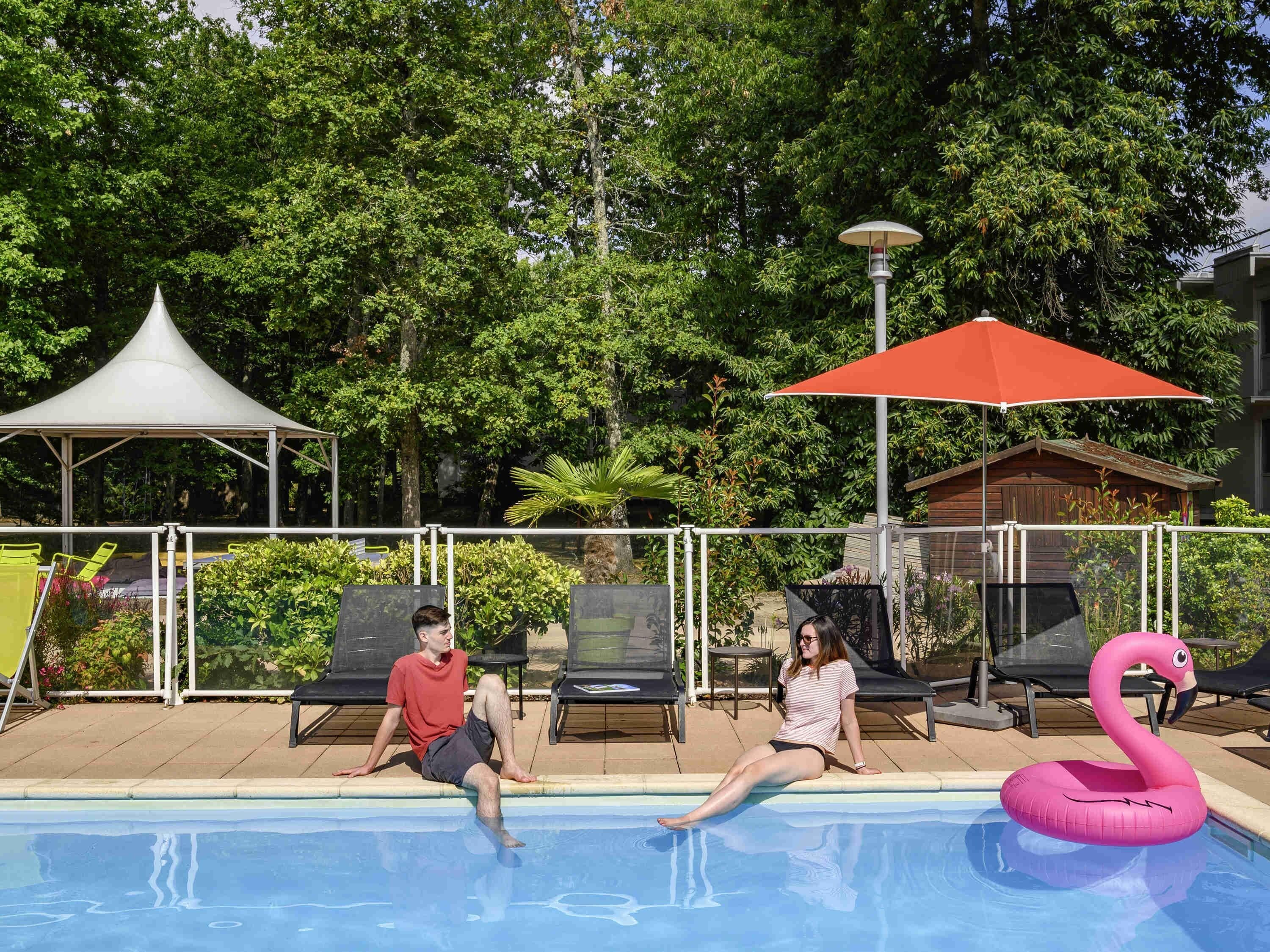 Piscina com cadeiras de descanso e um flutuador em formato de flamingo rosa.